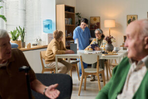 Caregiver speaking with residents in an assisted living community common area.